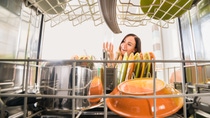 A young woman is taking a clean glass out of a dish washer.